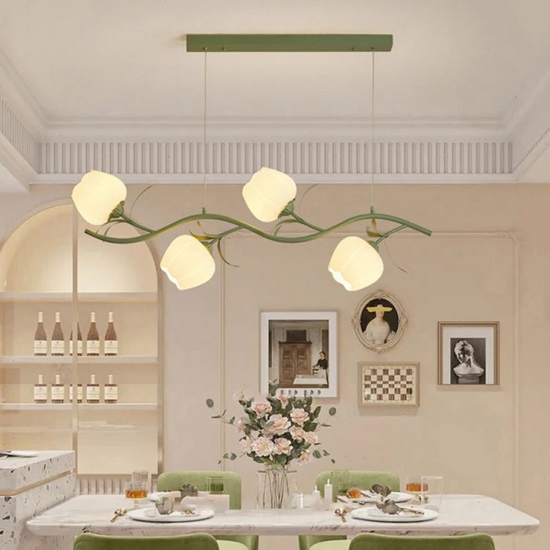 A green floral chandelier illuminating a dining room table set for a meal.