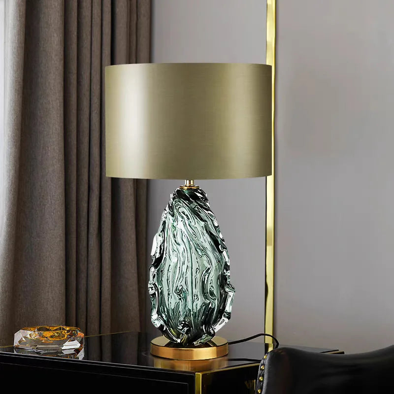 Decorative table lamp with a green marbled base and gold shade on a dark surface.