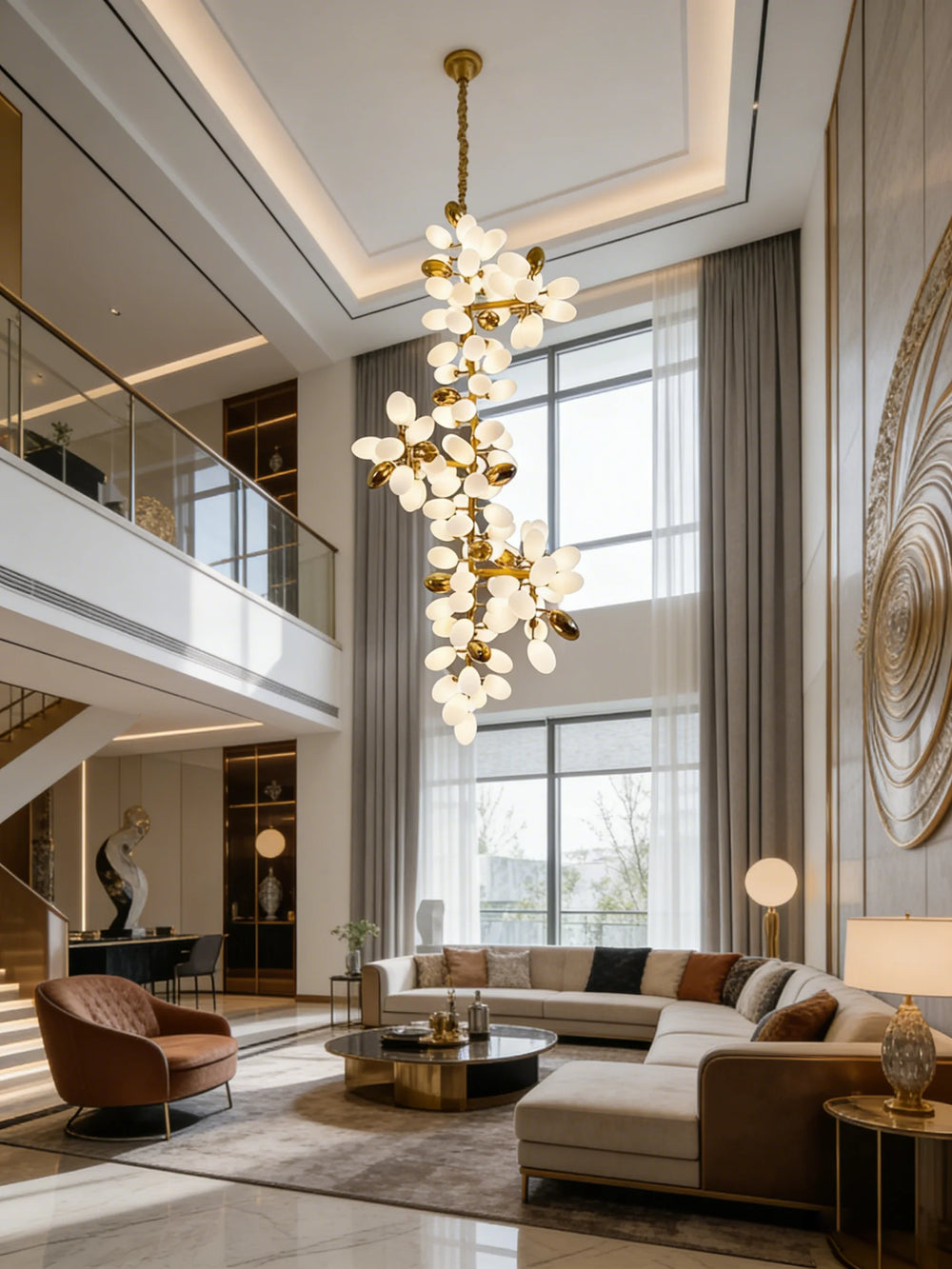 A spacious living area with a sectional sofa and a gold floral cluster chandelier hanging from the high ceiling.