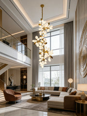 A spacious living area with a sectional sofa and a gold floral cluster chandelier hanging from the high ceiling.