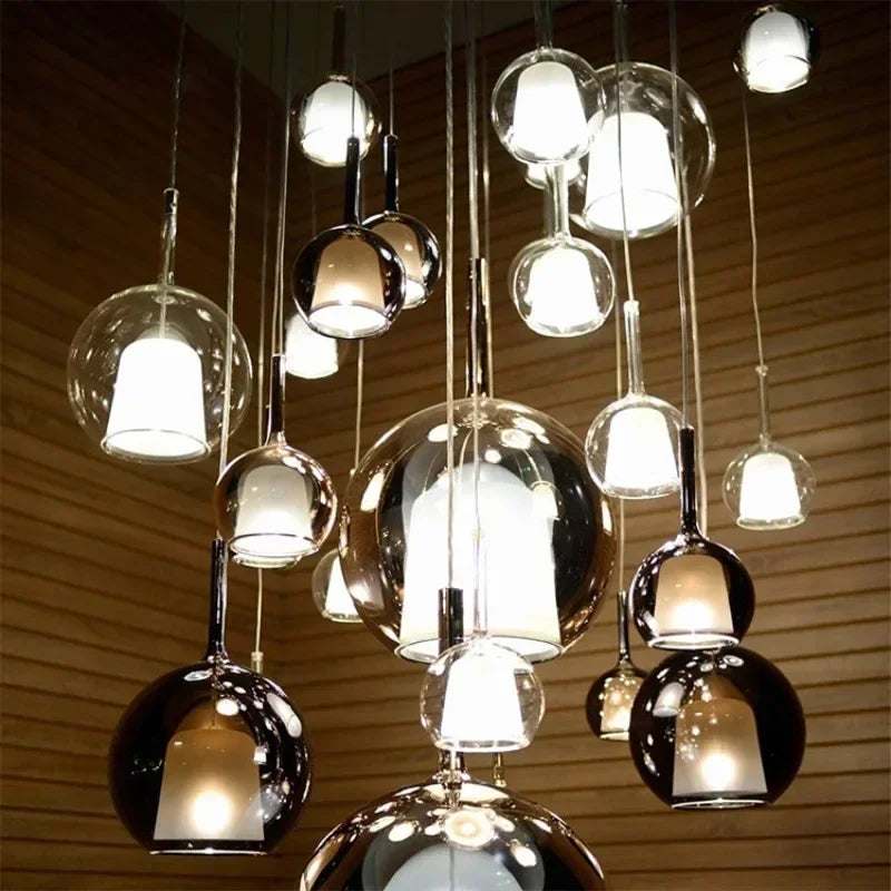 A collection of pendant lights with clear and smoked glass globes and metallic finishes, suspended from the ceiling.
