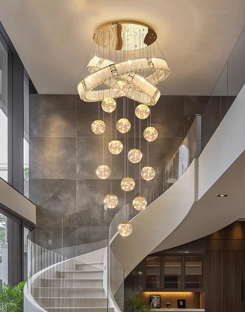 Chandelier hanging in a modern interior setting with staircase and wall lights.