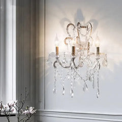 Crystal wall sconce with three lights on a white wall.