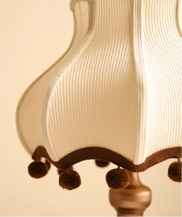 Close-up of a decorative lamp with a ribbed shade and brown trim on a beige background