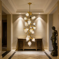 Gold floral-shaped chandelier with clear crystal accents hanging above a console table in a hallway.
