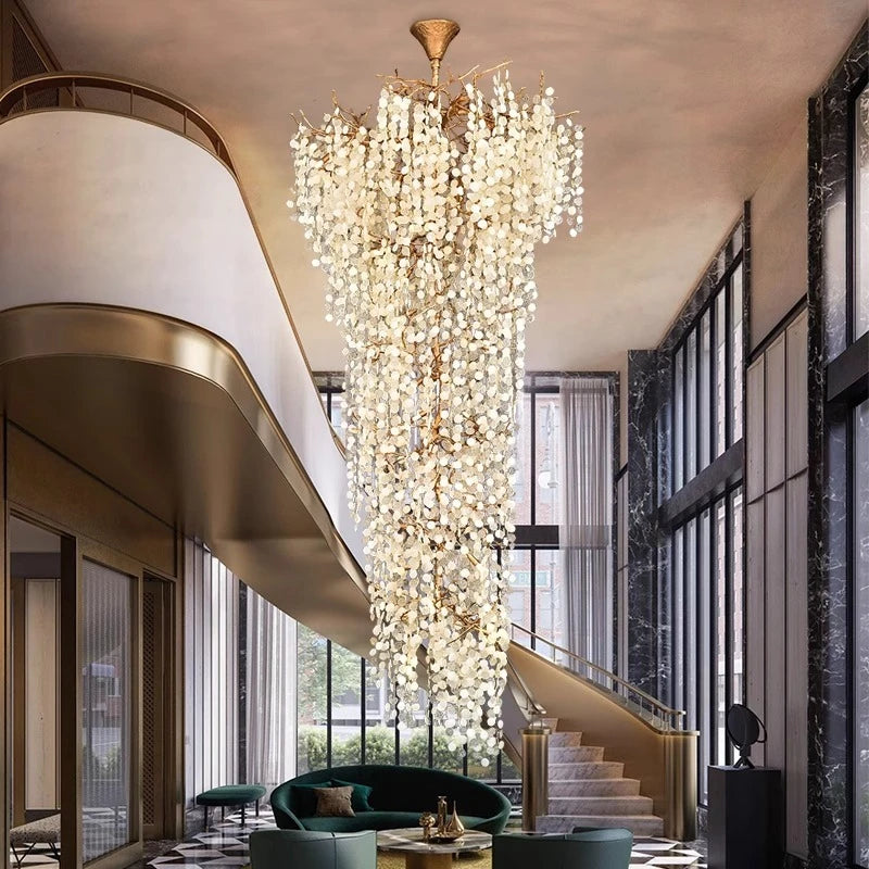 An expansive gold-framed crystal chandelier cascades in a luxurious foyer with a checkered marble floor and a curved staircase.