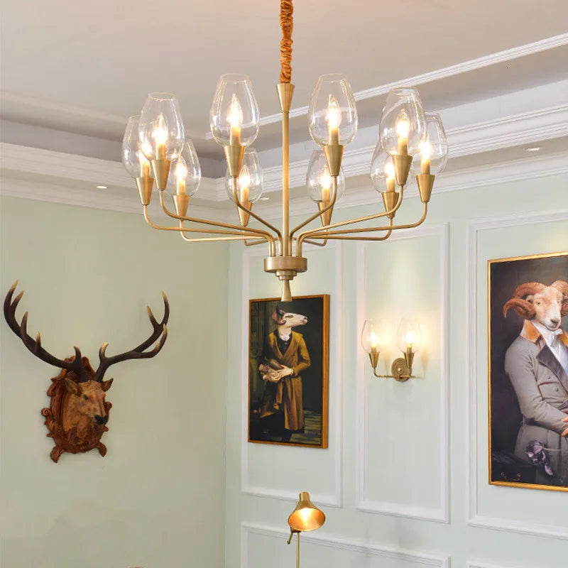 Gold chandelier with clear glass shades and artwork featuring animals and a wall sconce.