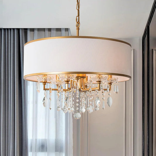 Gold drum shade chandelier with cascading clear crystals installed in a room with curtains.