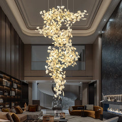 A grand hotel lobby featuring a large, illuminated gold ginkgo leaf chandelier.