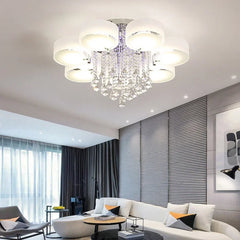 A modern living room with a sectional sofa, coffee table, and a crystal ceiling light fixture.