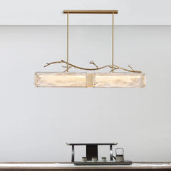 Rectangular glass pendant light with brushed gold branch accents against a plain background.