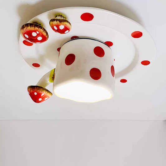 Close-up of a red polka dot ceramic coffee cup and mushroom ceiling light fixture.
