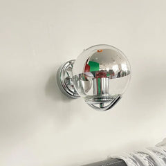 Wall-mounted light fixture with a reflective glass cover on a plain background