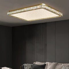 Square gold chandelier with faceted crystals and a frosted white diffuser, installed in a modern living room.
