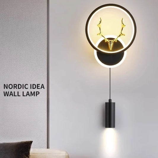Black wall sconce with circular LED halo and integrated antler design, with a hanging downlight cylinder, text overlay 'NORDIC IDEA WALL LAMP'.