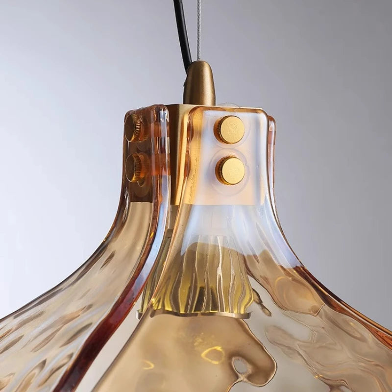 Close-up of a gold pendant light with a clear glass shade against a gray background