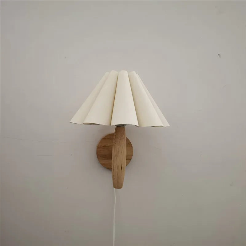 Wall-mounted lamp with a wooden base and white paper-like shade on a plain wall.