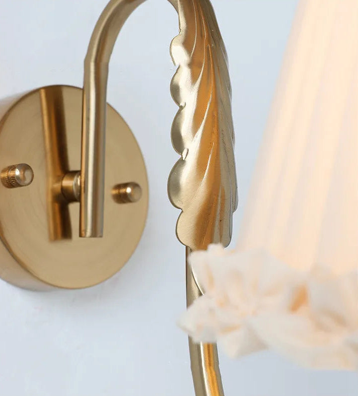 french retro wall lamp with pleated fabric shade and brass arm mounted on white wall