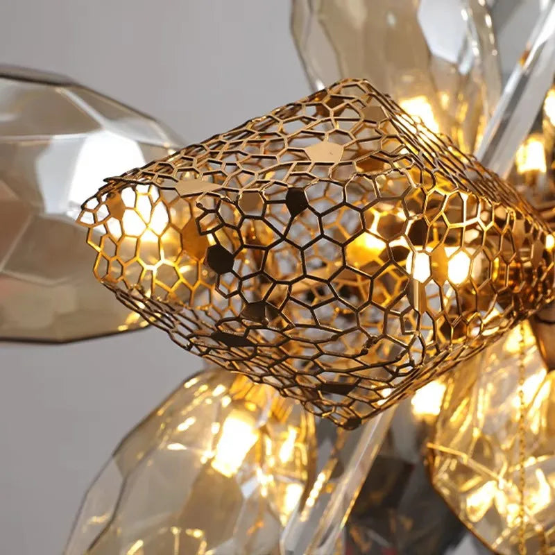 Close-up view of the intricate metallic mesh detail on the gold chandelier, with illuminated crystals behind it.