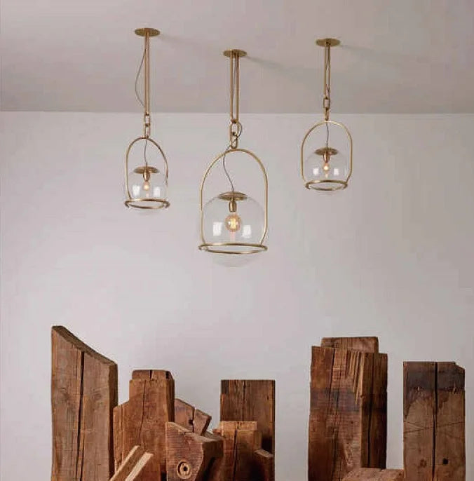Three gold glass ball pendant lights of varying heights are displayed together in a room setting.