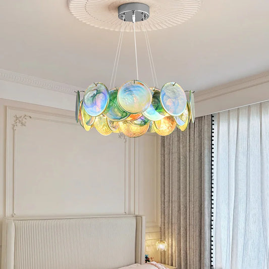 Close-up of a colorful Murano-style glass disc chandelier, showcasing the iridescent green, blue, and yellow hues.