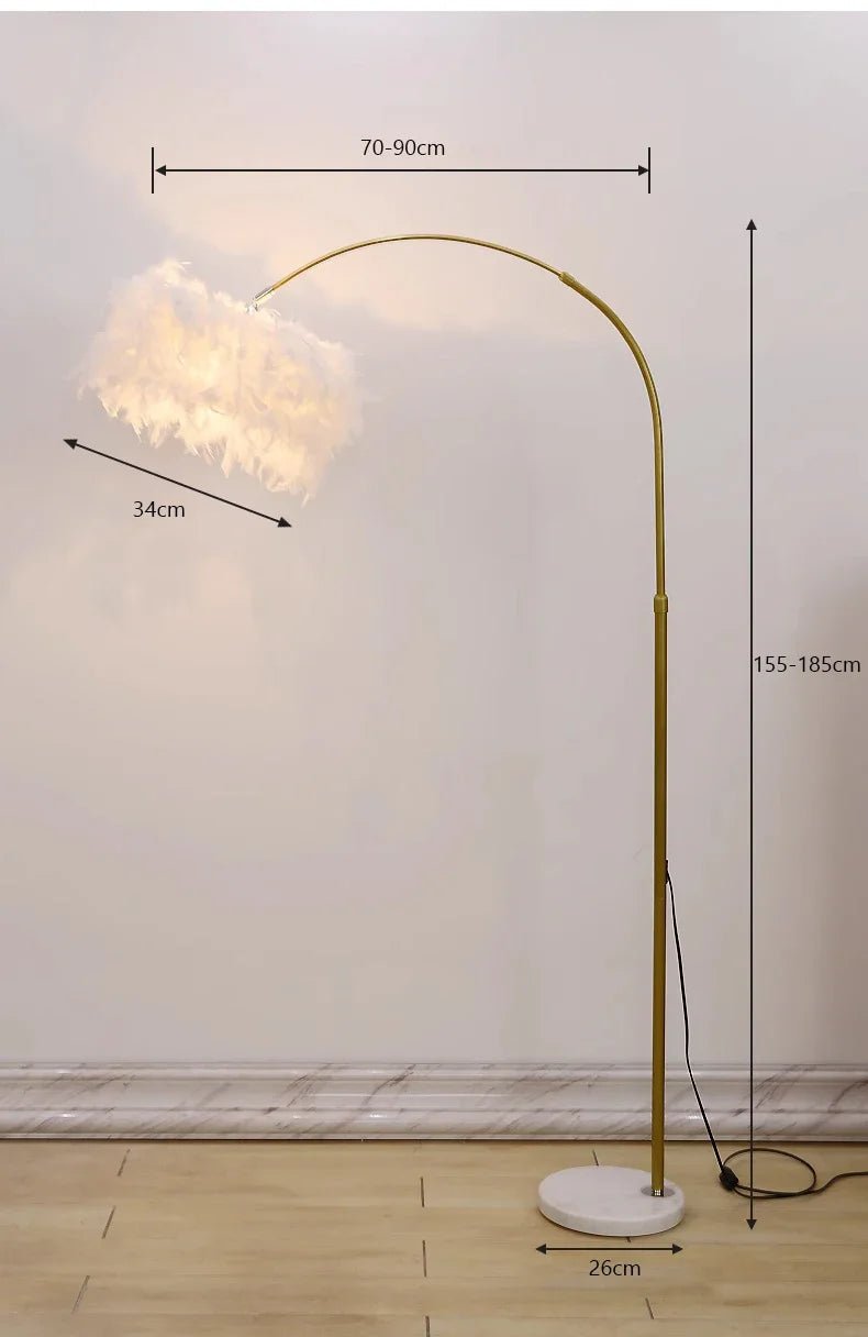 Gold floor lamp with feathered shade on a wooden floor against a white wall, with measurements indicated.