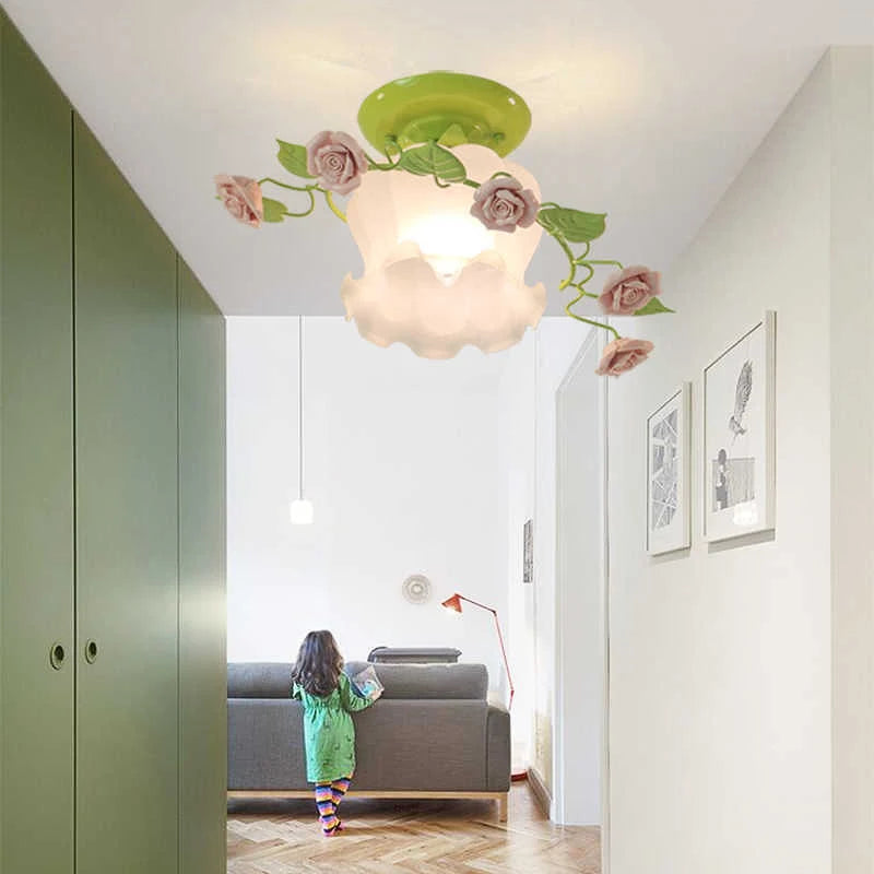 A hallway scene showing a green base floral ceiling light with pink roses and green leaves installed on the ceiling above a grey sofa.