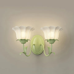Close-up of a green floral wall sconce with two frosted glass shades, mounted on a neutral wall.