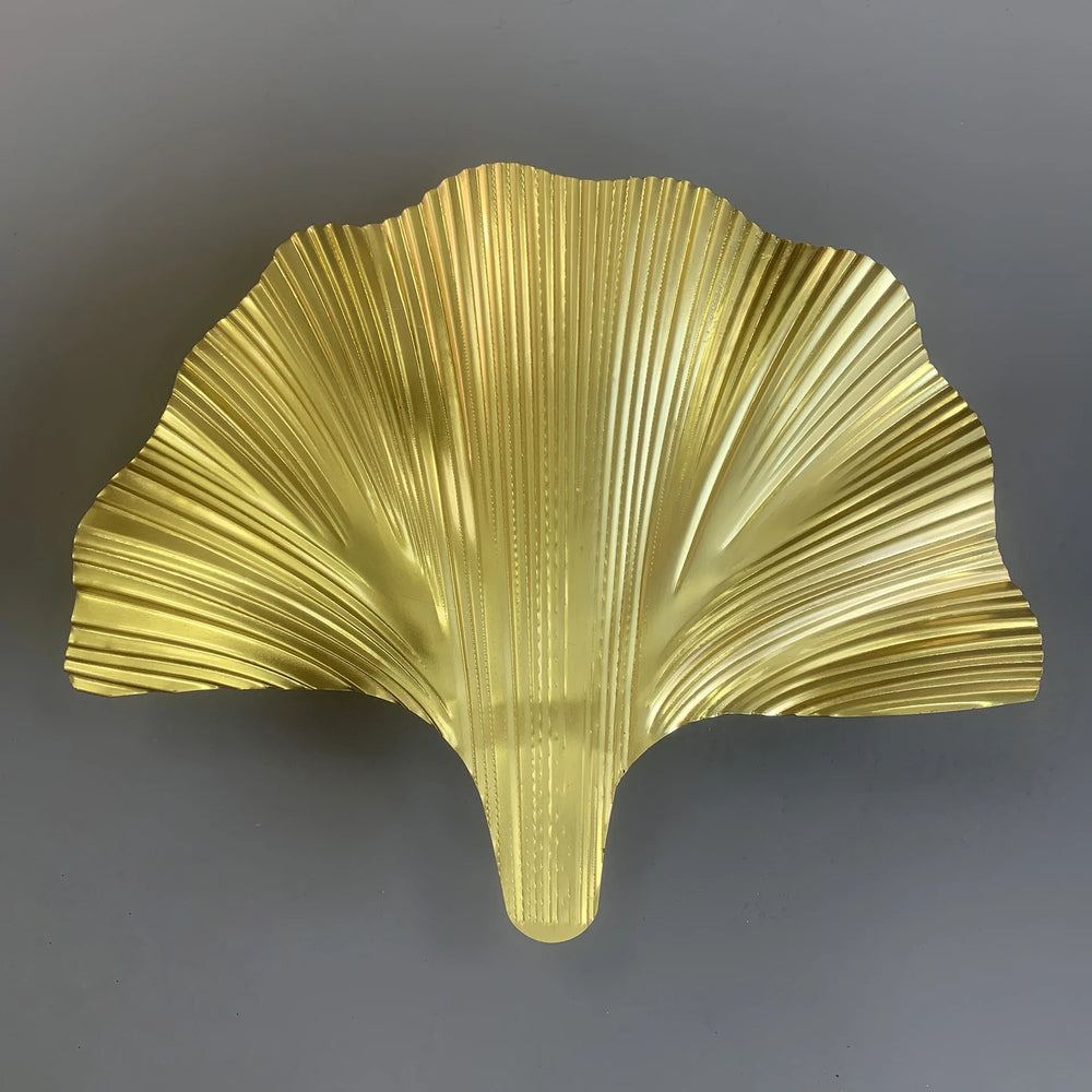 Gold leaf-shaped decorative item on a gray background