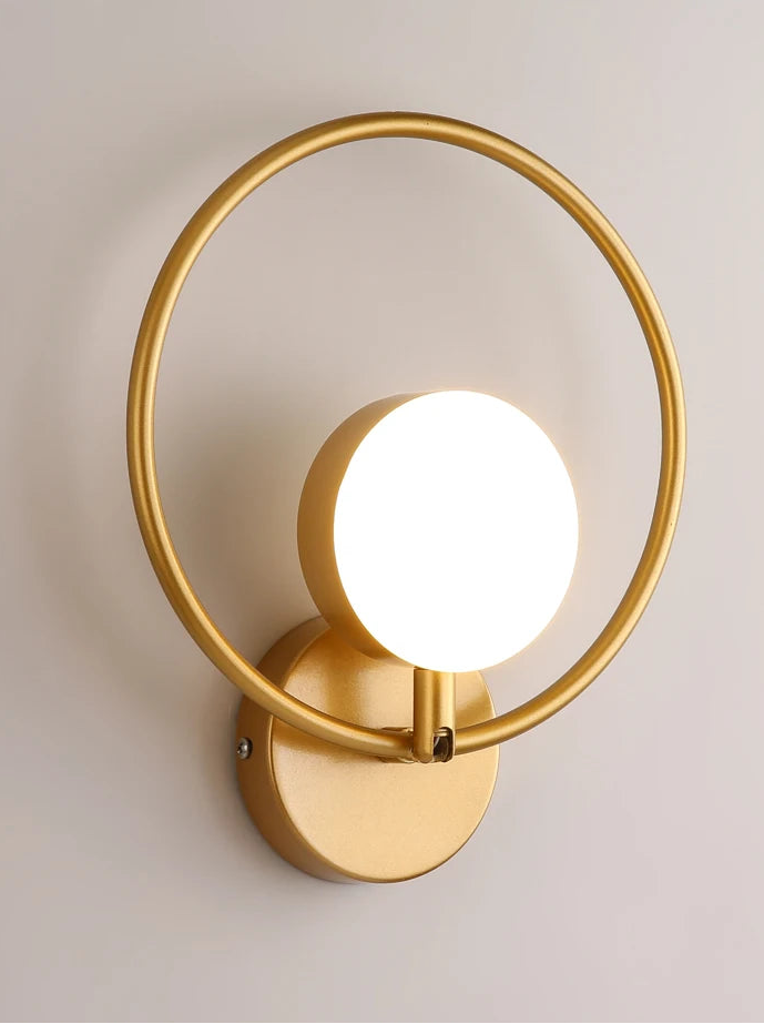 Gold wall lamp with a circular design on a light gray background