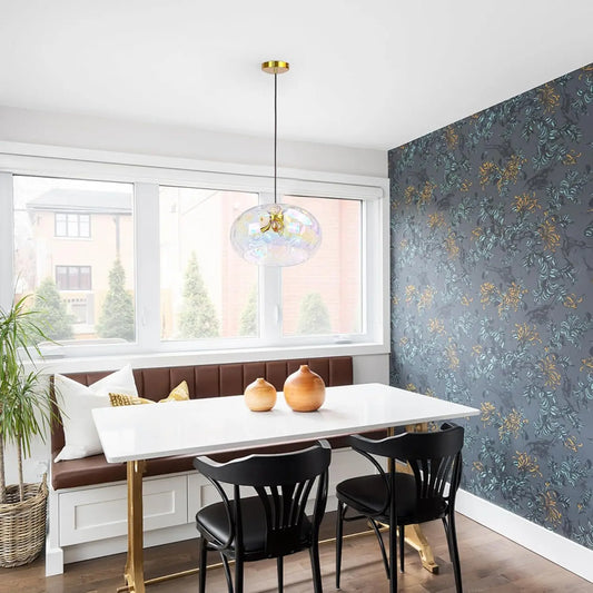 A modern dining room with a white table, brown bench seating, and a single gold water ripple glass pendant light hanging above the table.