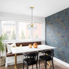 A modern dining room with a white table, brown bench seating, and a single gold water ripple glass pendant light hanging above the table.