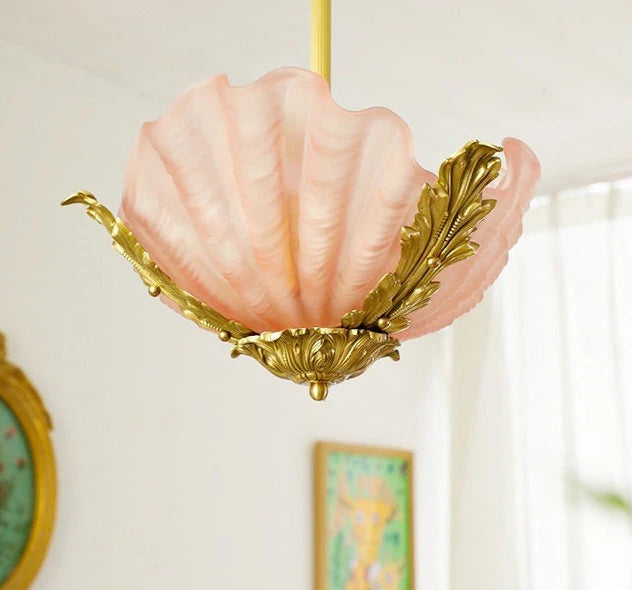 Close-up of a pink seashell glass pendant light, showcasing the textured glass and detailed gold leaf embellishments.