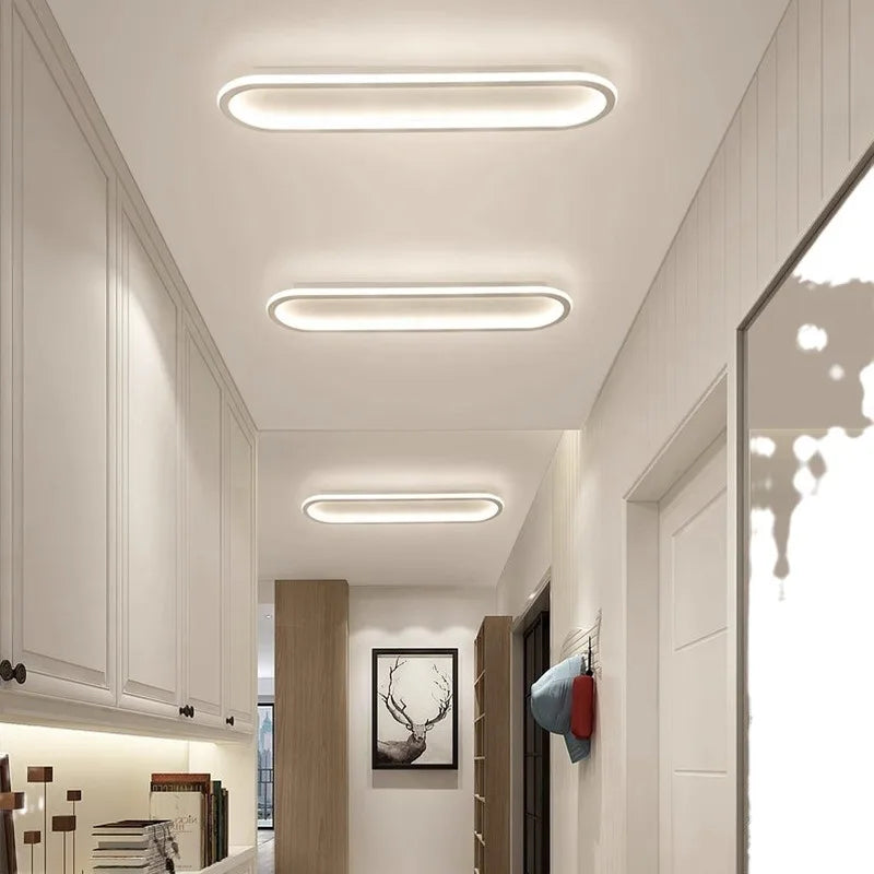 An interior hallway with multiple oval flush mount ceiling lights mounted on the ceiling.