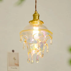 Close-up of a clear glass droplet pendant light with iridescent highlights, lit from within.