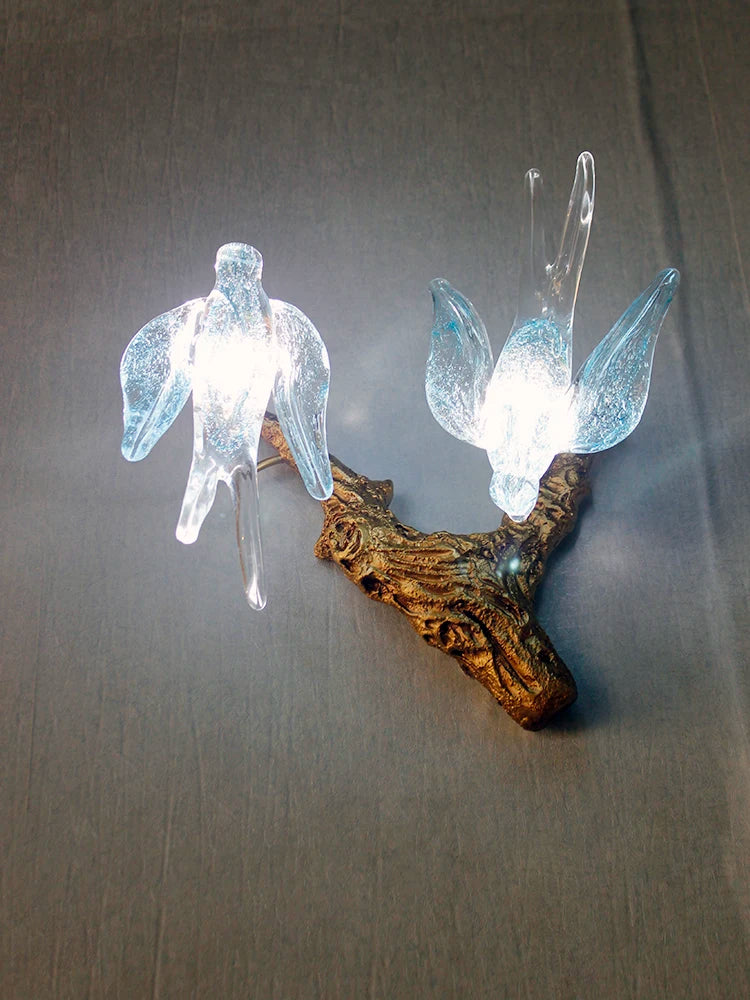 Decorative wall light fixture with angel wings on a plain background
