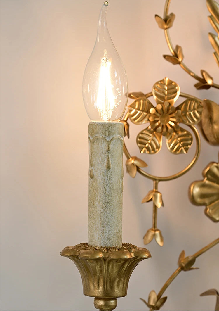 Decorative wall sconce with a light bulb inside, featuring gold and green colors.