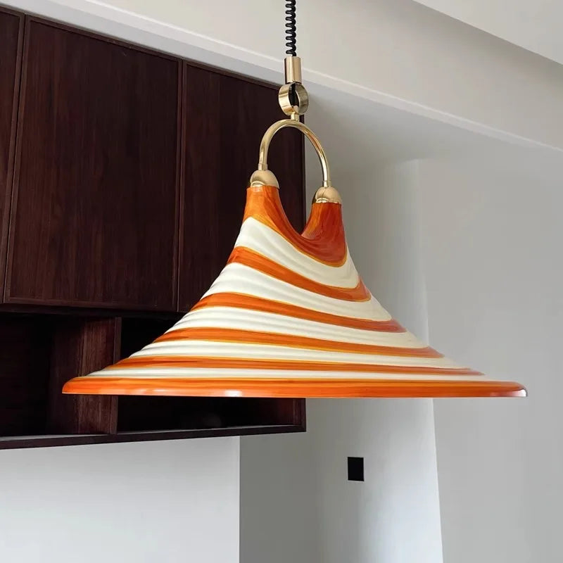 Close-up of the orange and white striped horn-shaped pendant light, showing the brass hanging hardware.
