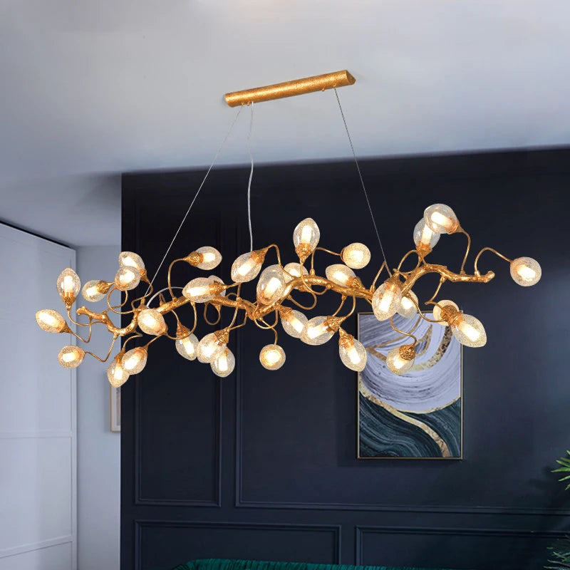 A gold branch chandelier with crystal fruit balls suspended from the ceiling over a dark blue wall and a green sofa.