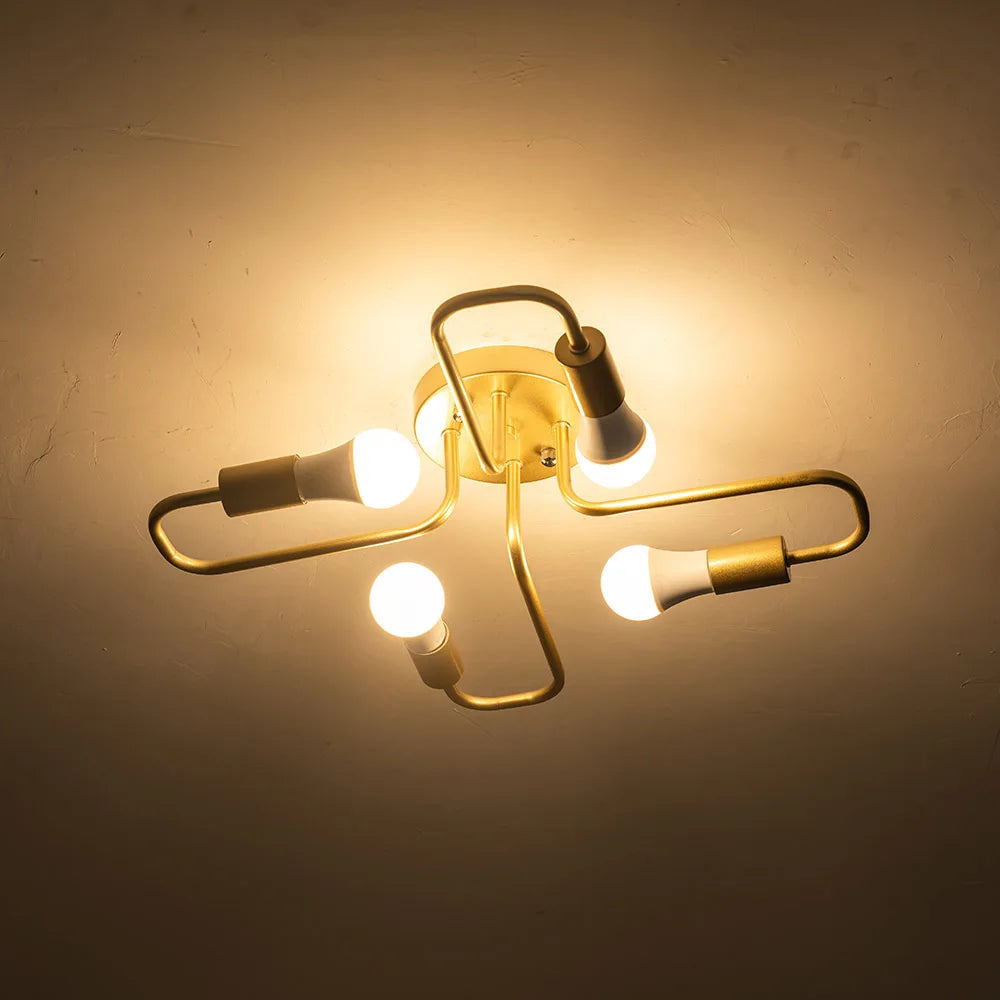 Gold metal starburst semi-flush ceiling light fixture with four lit LED bulbs against a dark ceiling