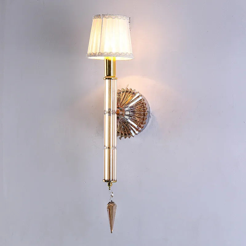 Decorative wall lamp with gold finish and crystal details on a plain background
