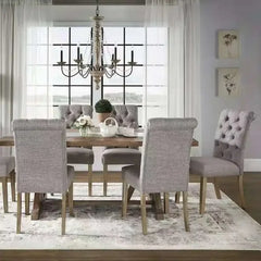 A dining room setting featuring a distressed wood candelabra chandelier with crystal accents hanging over a wooden table.