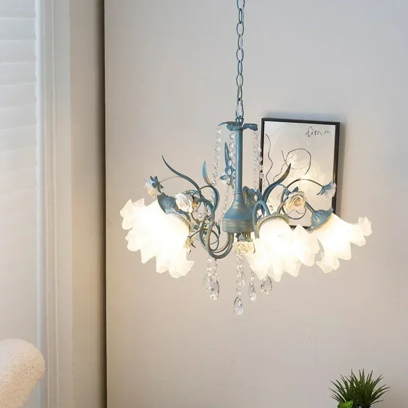 Side view of a blue floral ceramic chandelier with crystal accents, mounted on a white wall with a framed artwork.
