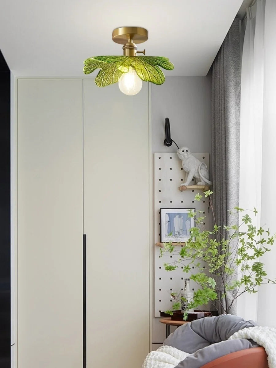 Modern ceiling light fixture with green leaf design in a room setting.
