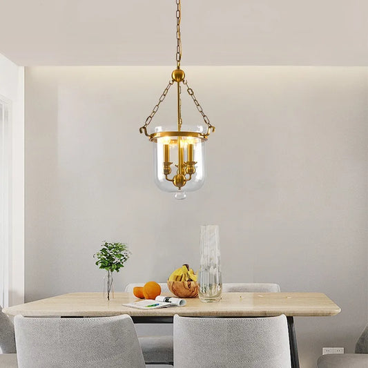 Polished copper and clear glass drum pendant light installed over a dining table