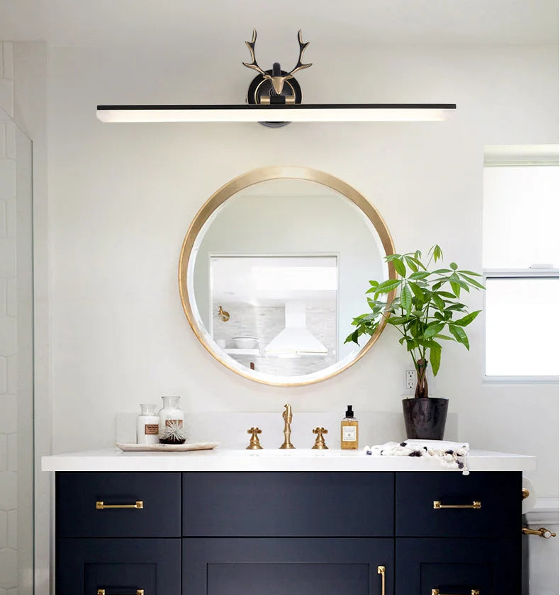 Bathroom vanity with round mirror, decorative items, and a plant.