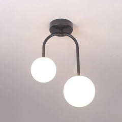 Close-up of a dark-finished semi-flush ceiling light with a U-shaped arm holding two white glass globes against a white ceiling.