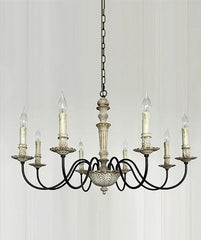 A white candelabra style chandelier with distressed finish and candle-shaped bulbs, hanging from a chain against a white paneled wall.