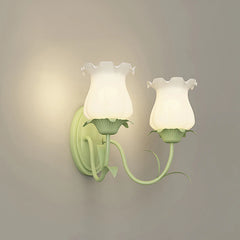 Two green floral wall sconces with frosted glass shades, illuminated on a plain wall.