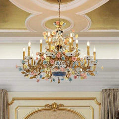 The gold ceramic rose floral chandelier installed in an opulent room with a decorative ceiling, casting a warm glow.